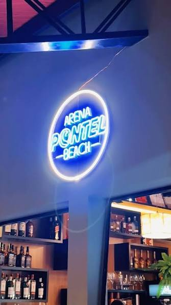 Letreiro neon da Arena Pontel Beach atrás do bar